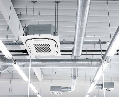 Ceiling mounted cassette type air condition units with other parts of ventilation system (tubes, cables and vents) located inside commercial hall with_