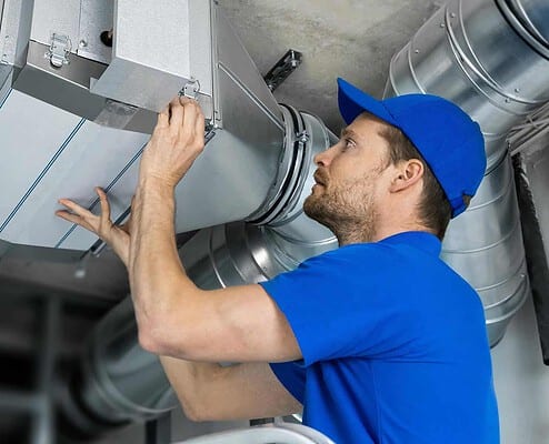 Image of a worker checking HVAC ducts.