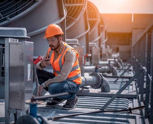 Image of a worker doing maintenance on an industrial HVAC system.