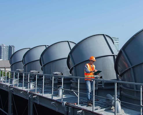Image of a worker inspecting HVAC cooling towers
