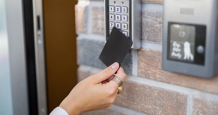 A woman scanning an access card on an electronic reader