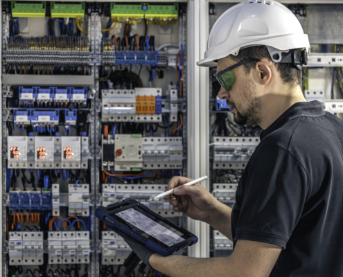 Man, an electrical working in a building automation system, uses a tablet.